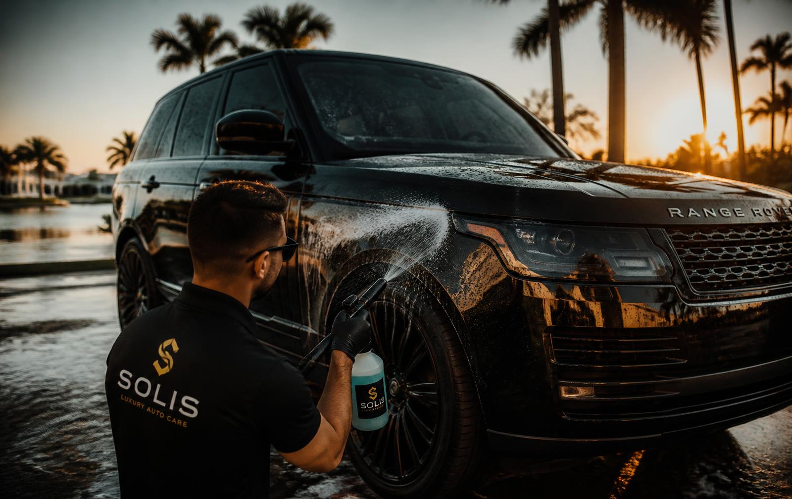 Detailer rinsing a glossy black SUV in a Maryville driveway at sunset